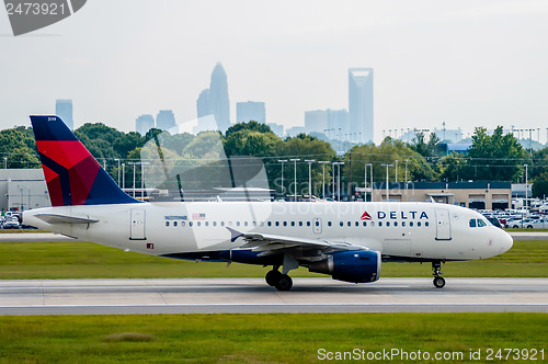 Image of Commercial jet on an airport runway with city skyline in the bac