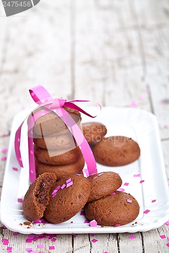 Image of fresh chocolate cookies with pink ribbon and confetti 