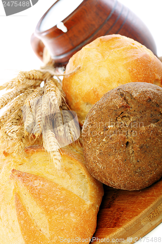 Image of Bread, wheat ears and milk in a clay mug.