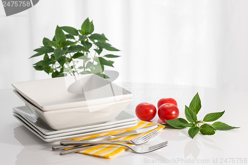 Image of Plates and kitchen utensils on a white table