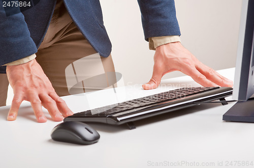 Image of Man Standing and Looking At A Computer Monitor