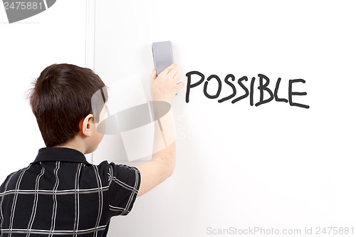 Image of happy little boy erasing text on white board