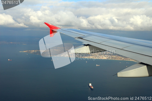 Image of cargo ships under wing of flying plane