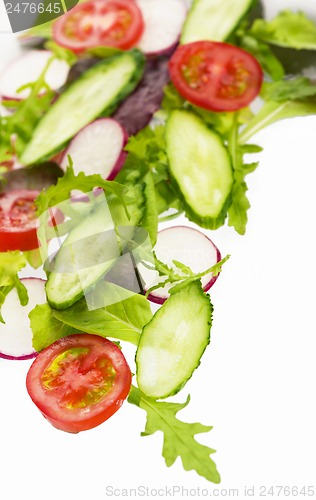 Image of cut cucumbers, garden radish, tomatoes and lettuce leaves