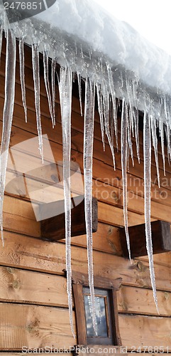 Image of Wooden house with big icicles on snow-covered roof