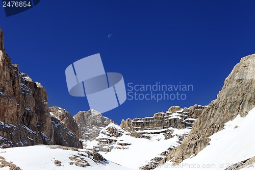 Image of Snowy rocks and cloudless blue sky with moon