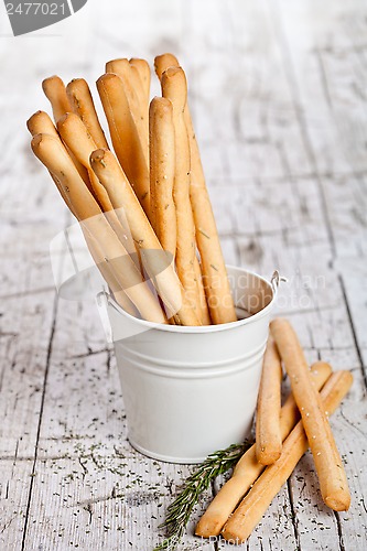 Image of white bucket with bread sticks grissini and rosemary 