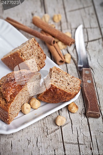 Image of sliced fresh buns, old knife,hazelnuts and cinnamon