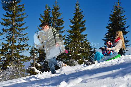 Image of family having fun on fresh snow at winter