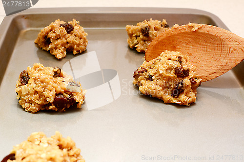 Image of Spooning oatmeal raisin cookie dough onto a baking sheet