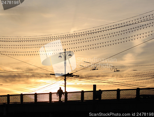 Image of A man walks across the bridge at sunset