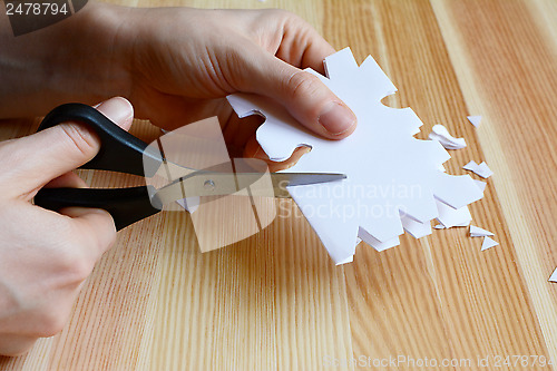 Image of Using scissors to cut out a paper snowflake shape