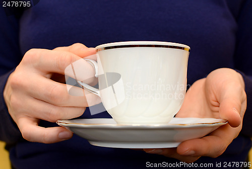 Image of Closeup of a woman's hands holding a teacup and saucer