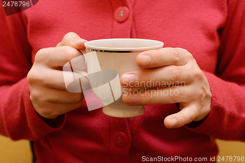 Image of Woman holding a teacup in two hands