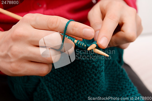 Image of Closeup of woman knitting with teal wool