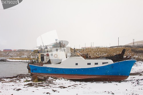 Image of the boat on the bank of the winter ocean