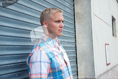 Image of attractive young adult man with blue eyes standing outdoor 