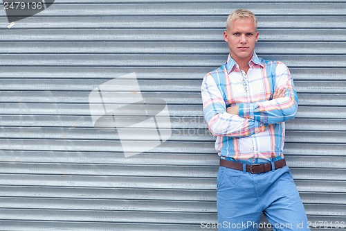 Image of attractive young adult man with blue eyes standing outdoor 