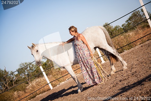 Image of young woman walking a road with horse