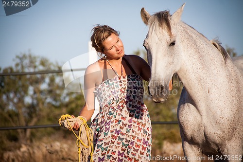 Image of young woman walking a road with horse