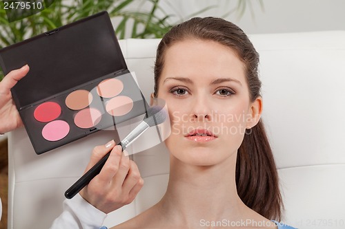 Image of apllying powder rouge make up on face portrait