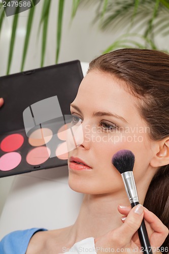 Image of apllying powder rouge make up on face portrait