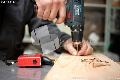 Image of Man with screwdriver. Focused on screw in front