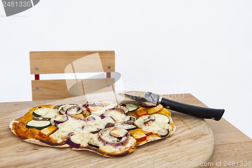 Image of pizza with cutter on small desk