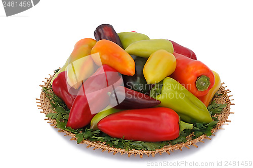 Image of Red, yellow and green peppers on the wicker dish on a white back