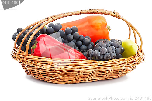 Image of Red, yellow pepper and grapes in a wicker basket on a white back
