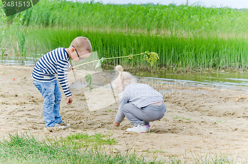 Image of  Boy and girl playing in the sand on the shore of Lake 