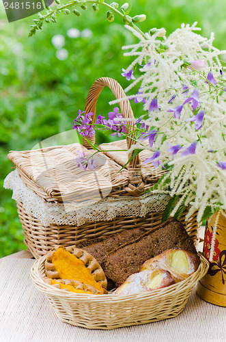 Image of Buns in a wicker basket and a bouquet of field flowers  