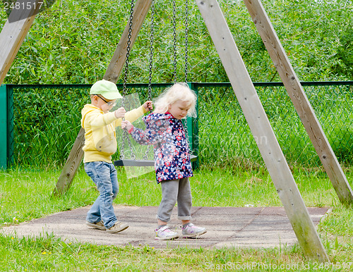 Image of Young children, a boy with a girl swinging on a swing