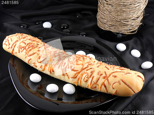 Image of sweet cake on black background, white stones and wine bottle