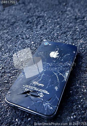Image of Black iPhone  with broken display laying on asphalt
