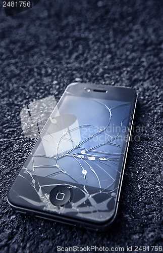 Image of Black iPhone  with broken display laying on asphalt