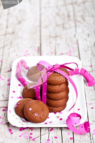 Image of plate of fresh chocolate cookies with pink ribbon and confetti 