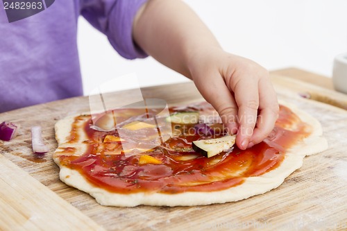 Image of hand of cld making fresh pizza