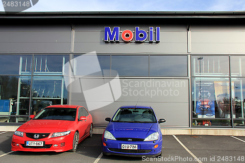 Image of Two Cars in front of a Shop with Mobil Sign