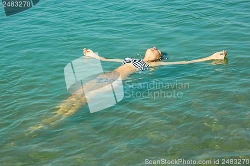 Image of Teen girl lying on the sea water surface