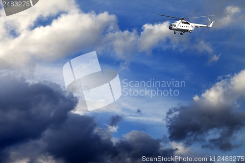 Image of Helicopter in blue sky with clouds