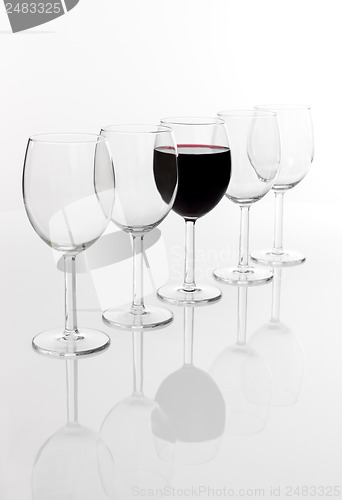 Image of Glass filled with red wine in a row of empty glasses