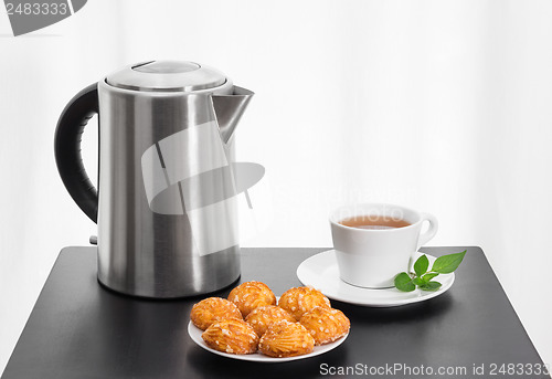Image of Electric kettle, cup of tea and cookies on a table