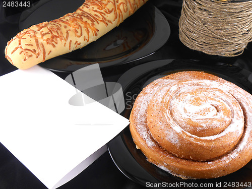 Image of sweet cake on black background, white paper and wine bottle