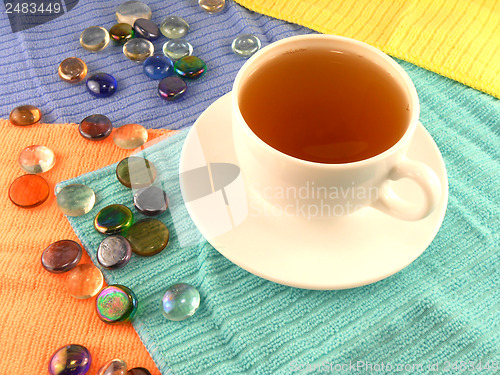 Image of Outdoor cup of tea in a white cup with stones on a material background