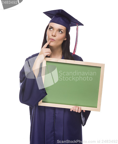 Image of Thinking Female Graduate in Cap and Gown Holding Blank Chalkboar
