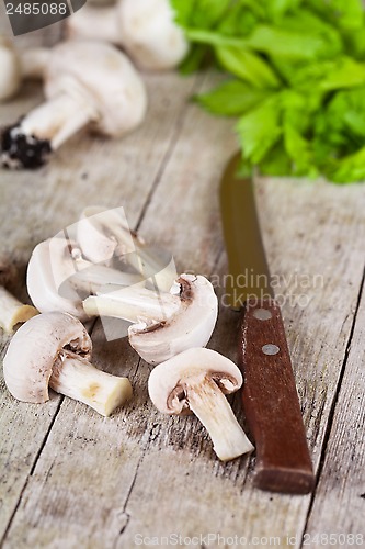 Image of  fresh sliced champignons with parsley and old knife