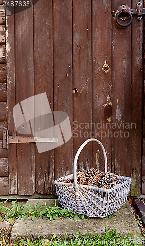 Image of Basket of fir cones by a wooden door