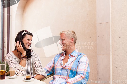 Image of happy young couple sitting outside cafe restaurant drinking coffee 