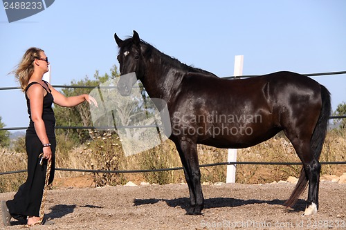 Image of young woman training horse outside in summer